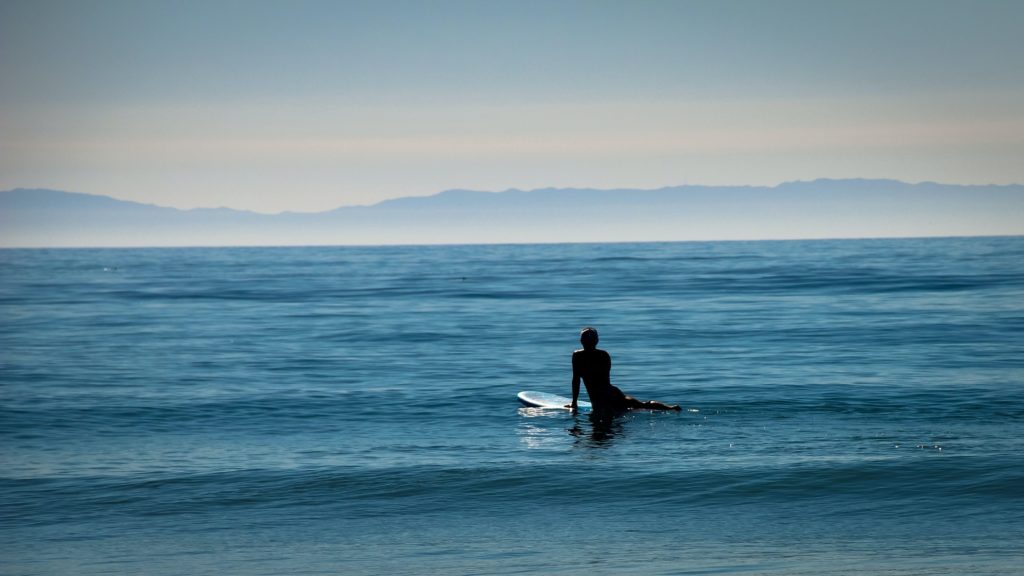 Die Surfer Myelopathie wird vermutlich durch die Überstreckung des unteren Rückens verursacht.  Auf diesem Bild wartet ein Surf-Anfänger  auf die nächste Welle. 